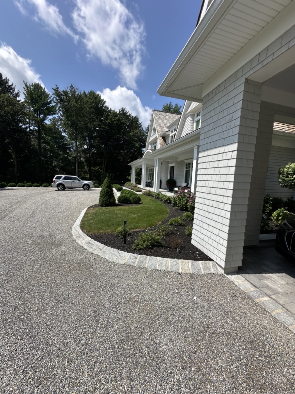 Curved granite cobble driveway island with boxwood